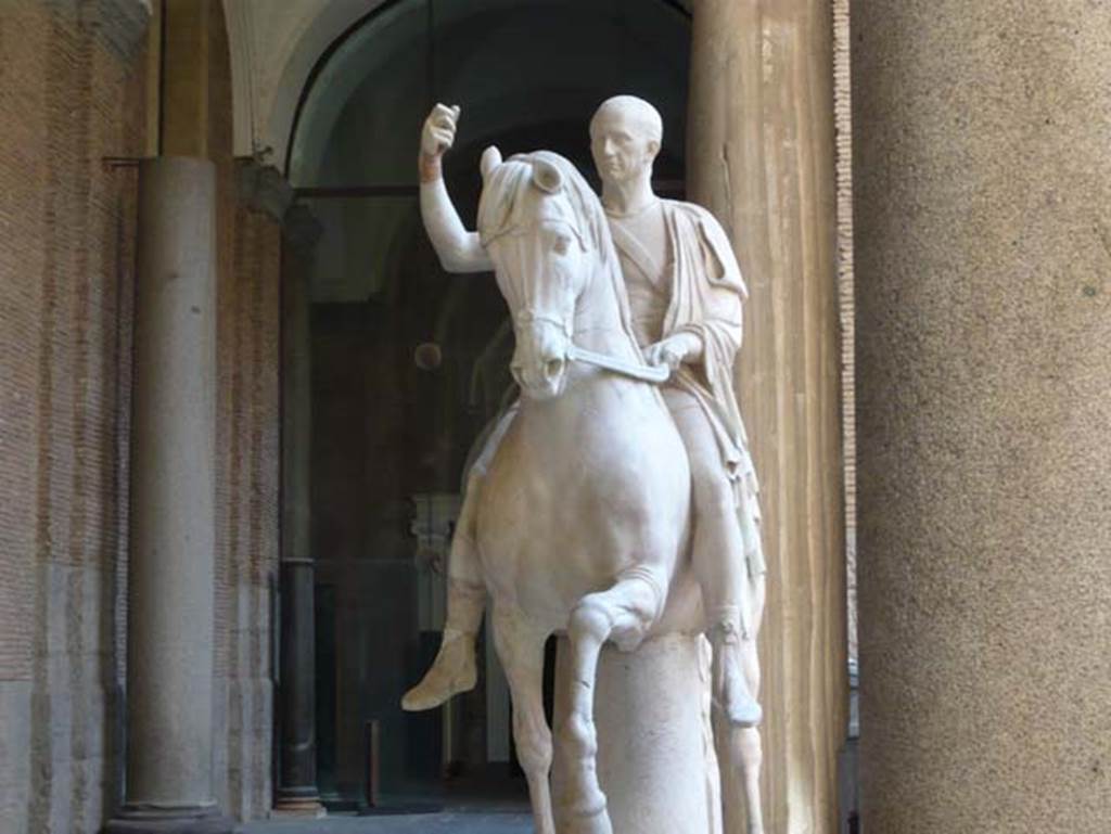 VII.16 Herculaneum. May 2010. Equestrian statue of the elder M. Nonius Balbus.
Now in Naples Archaeological Museum. Inventory number 6211.
Photo courtesy of Buzz Ferebee.
According to the information board in the Palazzo Reale at Portici in 2015, the statue was found in 1746 and was in pieces and headless. The sculpture was believed to depict Balbus the Younger’s father. Hence, during restoration, Canart made head for it after a portrait certainly showing Balbus senior, in compliance with the principles of Classicism, which called for full restoration of mutilated sculptures. Actually the two statues are believed to portray the same individual, being honoured respectively, by the towns of Nuceria and Herculaneum.